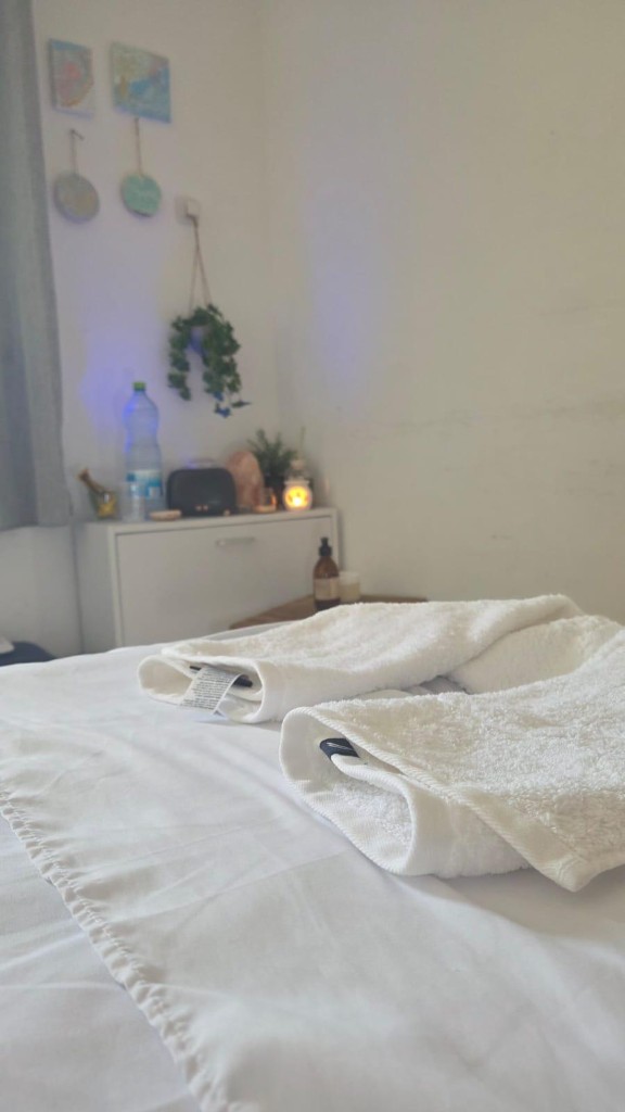 חדר טיפולים מרגיע עם מיטת עיסוי לבנה ומגבות מסודרות – קליניקה מגע הזהב באלעד